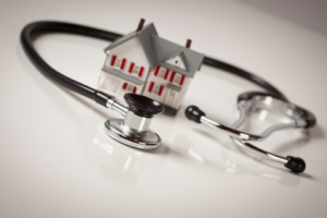 Stethoscope and Model House on Gradated Background with Selective Focus.